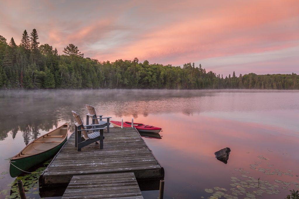 Canoe and kayak moored to a cottage dock at dawn - Ontario, Canada
